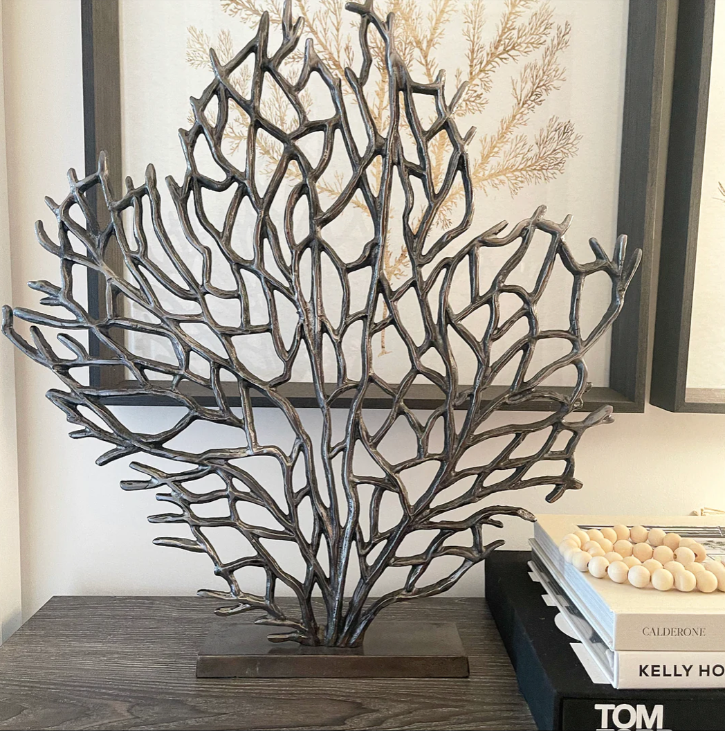 Alina ornament stands on a slim rectangular stand, and the sculpture spreads its branches upwards and outwards.Pictured on a sideboard with books next to the ornament and artwork in the background.