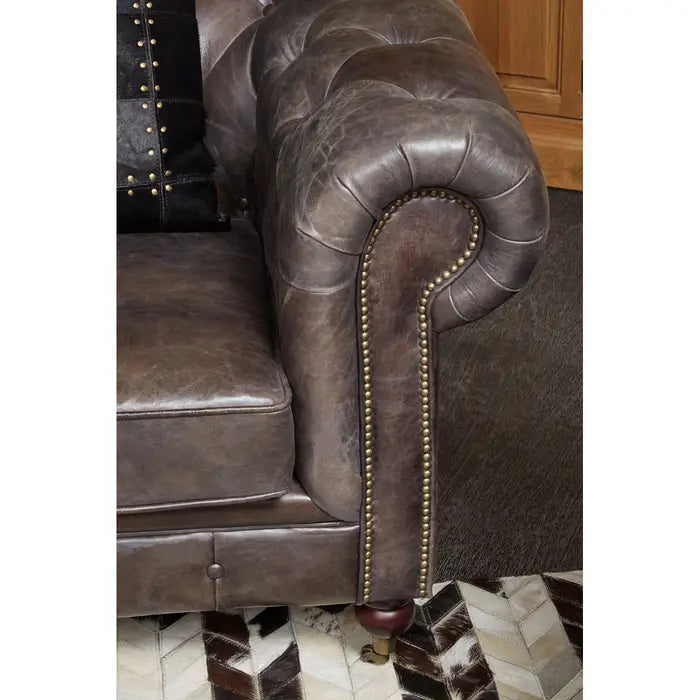 Metallic studs trace the lines of the large rolled armrests, and the traditional Chesterfield style.