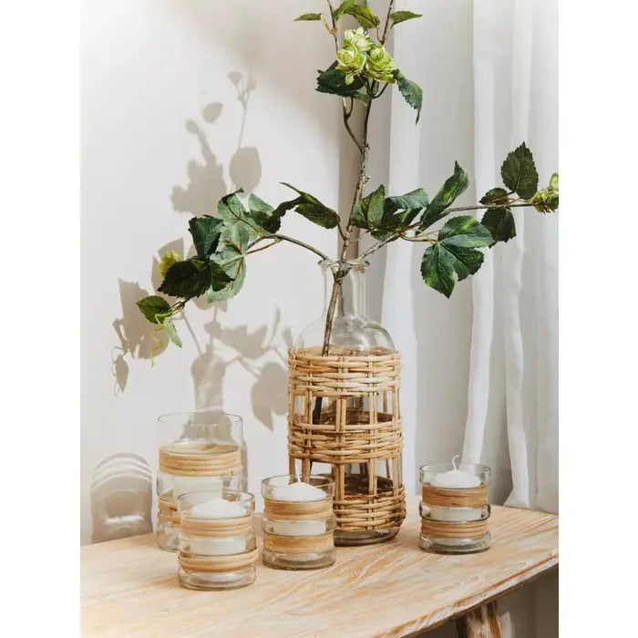 set of three tealight holders is made in glass, featuring a double belt of natural cane engulfing the glass structure.