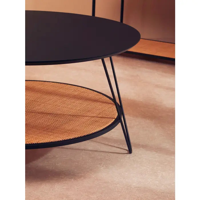 Coffee table with natural rattan shelf with black metal top and matching black metal legs.