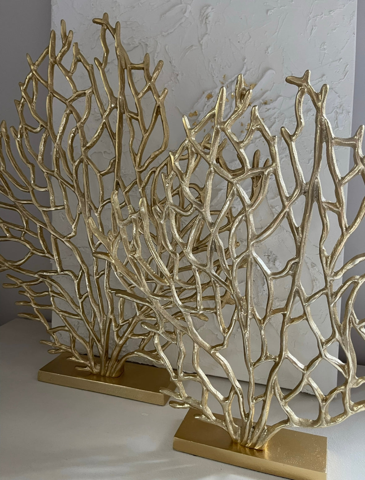 Gold ornament stands on a slim rectangular stand, and the sculpture spreads its branches upwards and outwards. 2 pictured with plain background. 